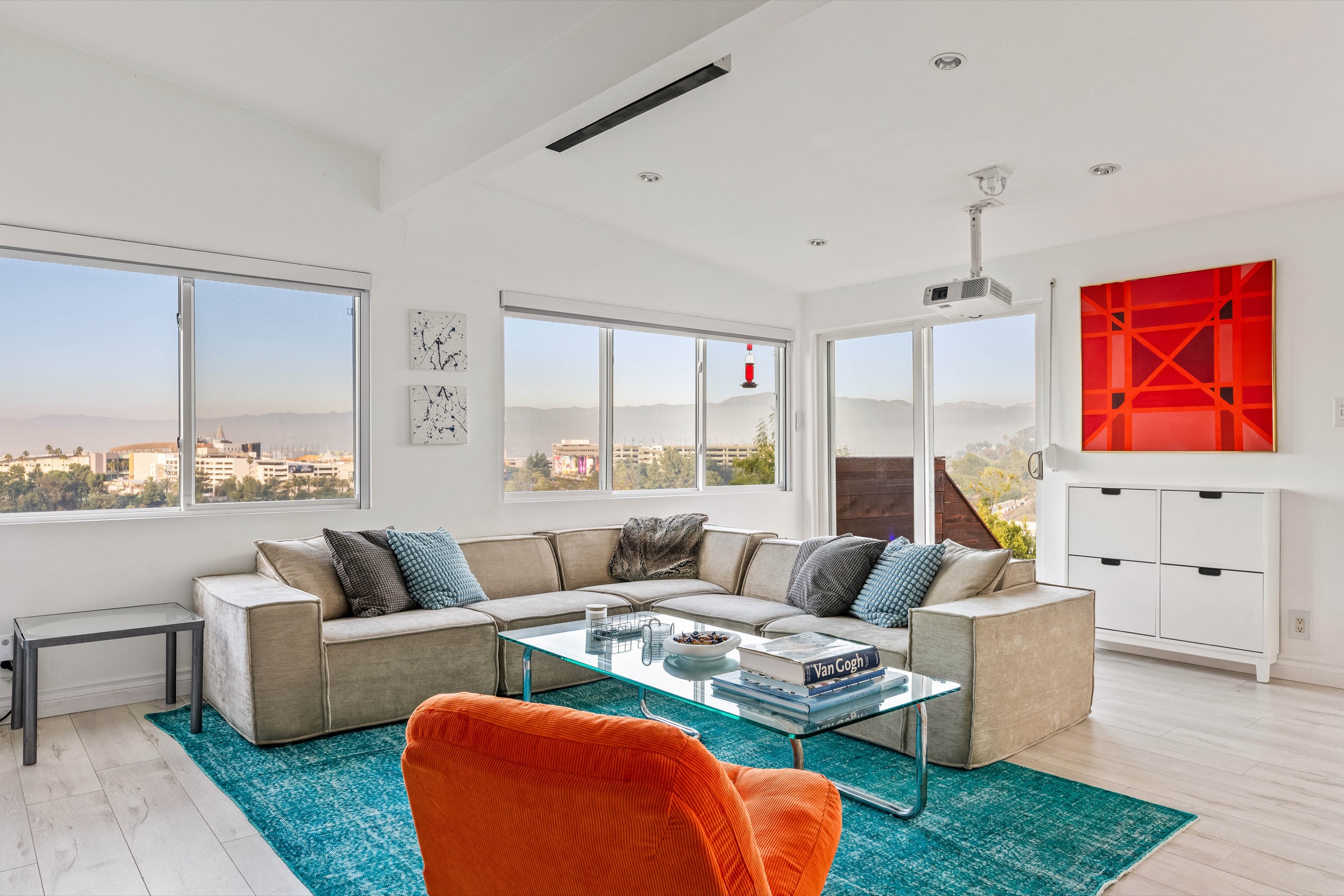 Sunlit living room and dining space with broad city views